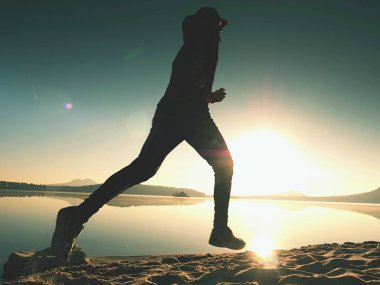  egzersiz ve göl kumsalda güneş doğarken uzanan bir adam. Sağlıklı bir yaşam tarzı. Yalnız genç fitness adam egzersiz sabah kumsalda