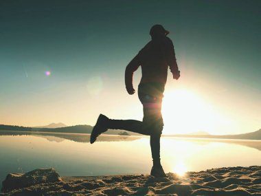  egzersiz ve göl kumsalda güneş doğarken uzanan bir adam. Sağlıklı bir yaşam tarzı. Yalnız genç fitness adam egzersiz sabah kumsalda