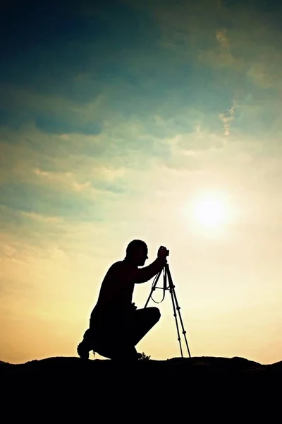 Fotógrafo de natureza com tripé em penhasco e pensamento. Paisagem nebulosa sonhadora, nebuloso nascer do sol no vale abaixo — Fotografia de Stock