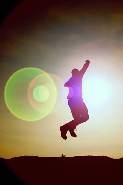 Saltando hombre. Joven loco está saltando en el fondo del cielo colorido.Silhouette de hombre saltando y hermoso cielo puesta de sol . — Foto de Stock