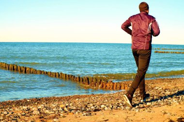 Adam siyah Çalıştır ve egzersiz dalgakıran, sahilde.