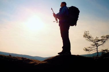 Alone adult man backpacker at sunrise at open view on mountain peak clipart
