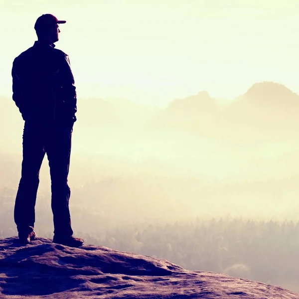 Einsamer Wanderer mit roter Mütze steht auf Gipfel im Felsenreich-Park und schaut in die Sonne — Stockfoto