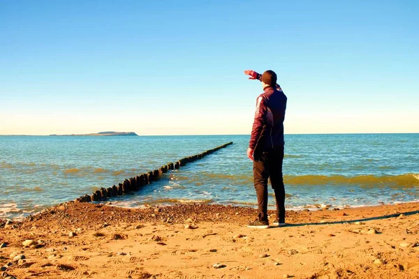 Großer Mann im schwarzen Anzug beim Dehnen am steinigen Strand an der Buhne. — Stockfoto