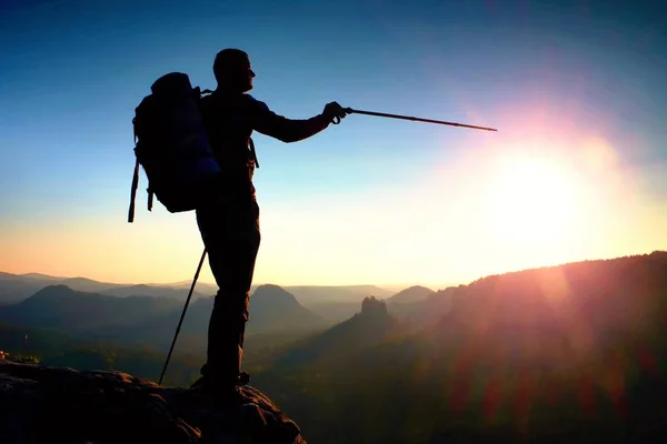 Scharfe Silhouette eines großen Mannes auf dem Gipfel des Berges mit Sonne im Rahmen. Reiseführer in den Bergen — Stockfoto