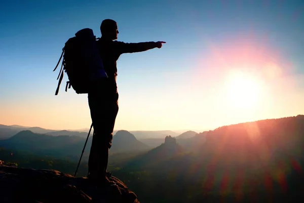 Silhouette nette d'un grand homme au sommet de la montagne avec soleil dans le cadre. Guide touristique en montagne — Photo