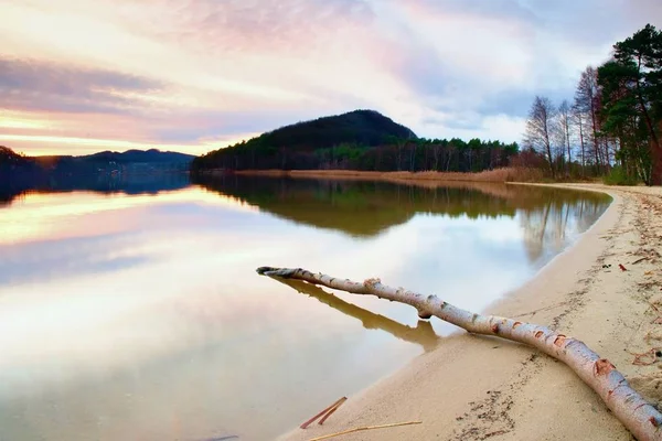 Longa exposição da margem do lago com tronco de árvore morta caído na água Noite de outono após o pôr do sol . — Fotografia de Stock