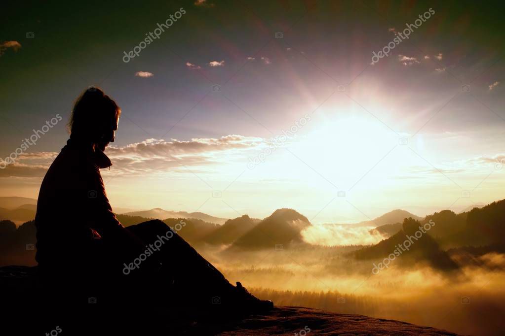 Beautiful  young long hair girl tourist enjoy daybreak on the sharp corner of sandstone rock and watch over valley to Sun.