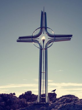 Çelik çapraz Alpleri'nde dağın zirvesinde kaldırdı. Keskin tepe. Şafak Güneş gökyüzünde