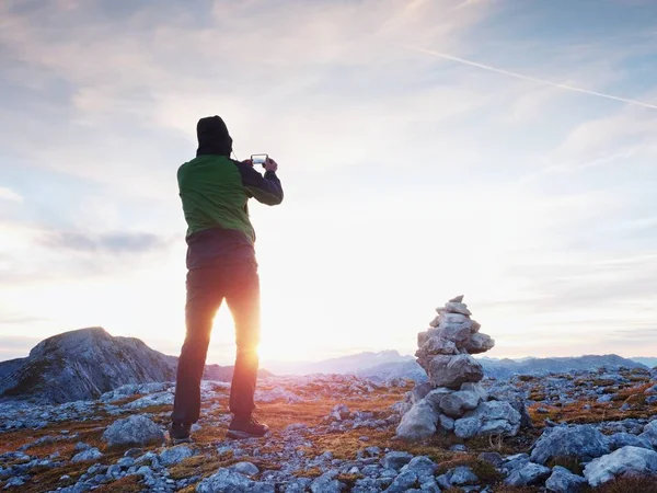 Sám tramp má telefon fotografie v horách. Muž na vrchol hory Alpy. Pohled do purpurové nebe — Stock fotografie