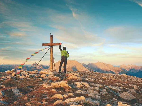 Alone man climber near the summit cross on peak, Dolomite Alps, Austria. Sunny windy evening. — Stock Photo, Image