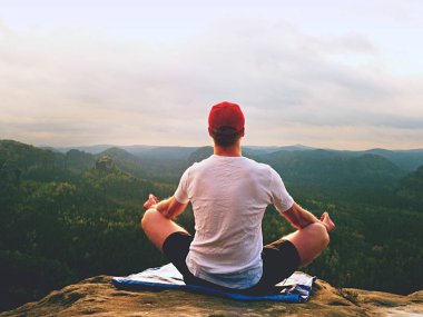 Yalnız adam pratik Yoga poz kayalık tepe üzerinde oturuyor. Adam puslu sabah içinde meditasyon yapmak 