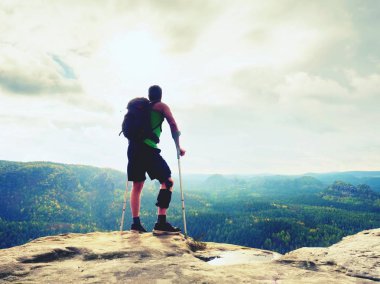 Doğada bir koltuk değneği olan adam. Kırık bacak koltuk değneği ile turist. Yaralı bacak bandaj ile seyahat