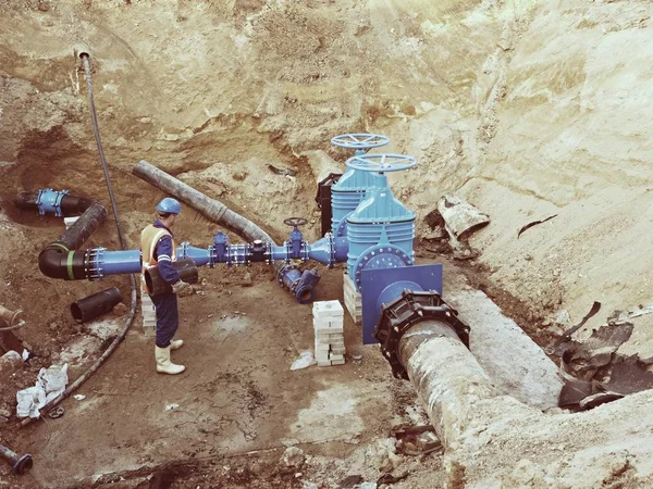 Trabajador subterráneo en válvula de compuerta, reconstrucción del sistema de agua potable — Foto de Stock