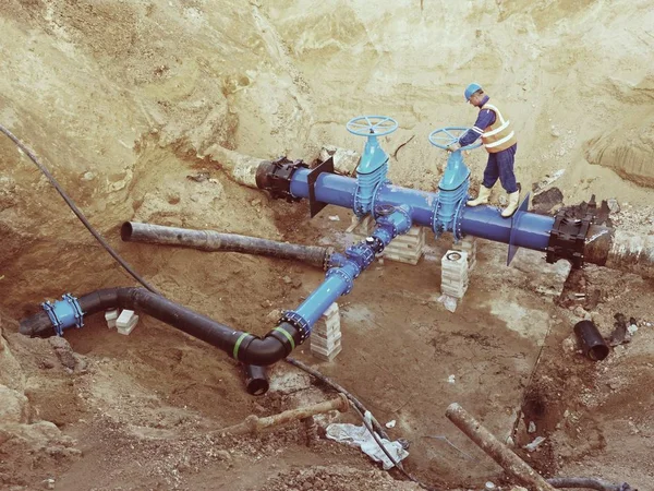 Trabajador subterráneo en válvula de compuerta, reconstrucción del sistema de agua potable — Foto de Stock