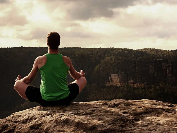 Hombre en la cima de la montaña en pose de yoga. Ejercicio yoga en el borde con una vista impresionante —  Fotos de Stock