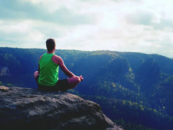 Hombre en la cima de la montaña en pose de yoga. Ejercicio yoga en el borde con una vista impresionante —  Fotos de Stock