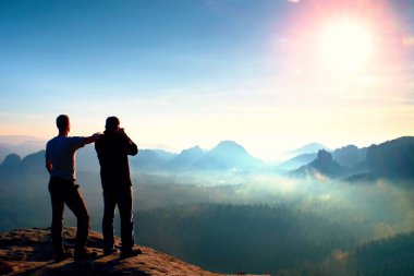 İki arkadaş. Uzun yürüyüşe çıkan kimse düşünme ve fotoğraf meraklısı fotoğraf kalış cliff üzerinde alır. Rüya gibi adamlara manzara, mavi puslu gündoğumu bir güzel vadi