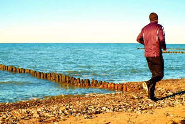 Uzun boylu adam çalıştıran ve dalgakıran, taşlı plajda egzersiz karanlık sportswer.