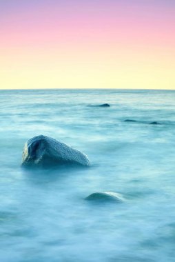 Denizde romantik atmosferi huzurlu sabah. Büyük kayalar pürüzsüz dalgalı denizden çıkmış. Pembe ufuk 
