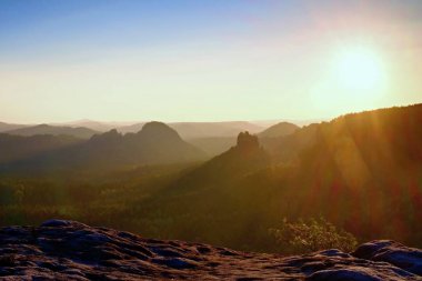 Güneşli fişekleri lens içinde. Renkli daybreak. Puslu bir güzel tepelerde uyanış. Hills doruklarına sisli kökenli yapışkanlık dışarı