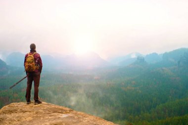 Sırt çantası ve Polonyalılar cliff ve derin puslu Vadisi feryat izlerken ile turist. Güneşli bahar günü dağlarda.