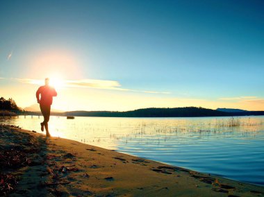Çalışan adam. Erkek koşucu gündoğumu sırasında kumsalda koşu