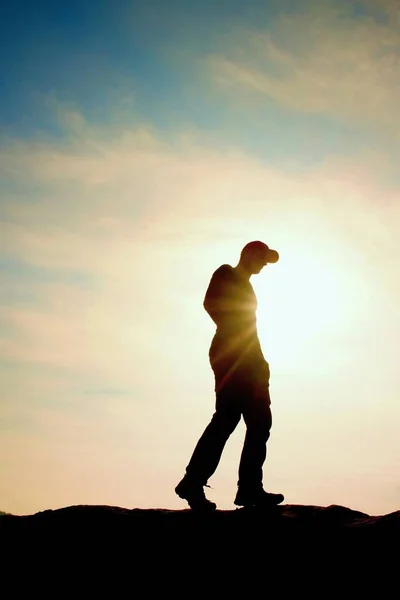 Hombre con gorra roja en pico rocoso. Hombre caminando sobre la cumbre rocosa hacia el Sol. Hermoso momento el milagro de la naturaleza . — Foto de Stock
