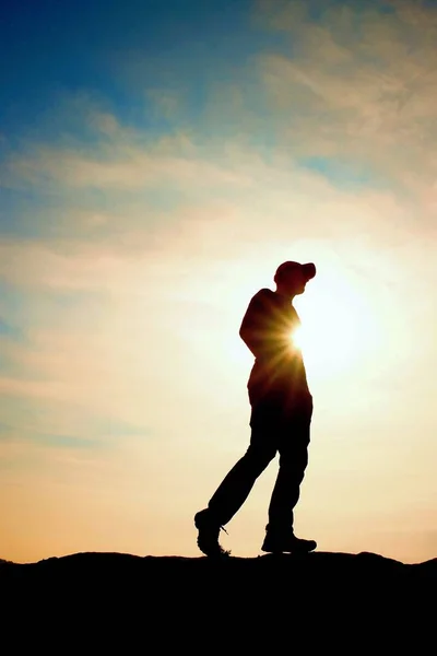 Caminante en sudadera roja con gorra roja en pico rocoso. Hombre vigilando valle a sol. Hermoso momento — Foto de Stock