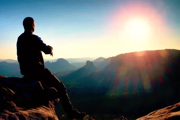 Uomo turista sedersi finalmente sulla vetta della montagna. Viaggio in montagna. Sole all'orizzonte — Foto Stock