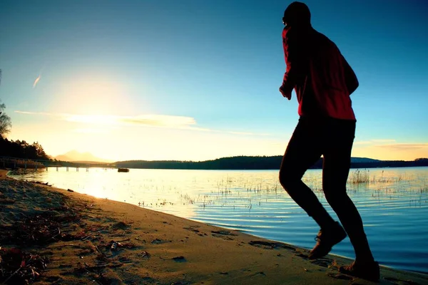 Sportowy człowiek robi Jogging rano na plaży w jasny świt sylwetki — Zdjęcie stockowe