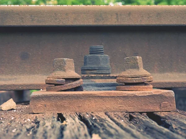 Detalj av rostiga skruvar och mutter på gamla järnvägsspår. Rooten trä slips med rostiga muttrar och bultar. — Stockfoto