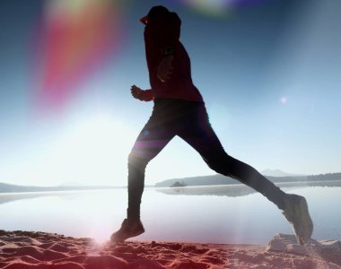  egzersiz ve göl kumsalda güneş doğarken uzanan bir adam. Sağlıklı bir yaşam tarzı. Yalnız genç fitness adam egzersiz sabah kumsalda