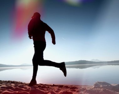  egzersiz ve göl kumsalda güneş doğarken uzanan bir adam. Sağlıklı bir yaşam tarzı. Yalnız genç fitness adam egzersiz sabah kumsalda