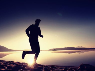  egzersiz ve göl kumsalda güneş doğarken uzanan bir adam. Sağlıklı bir yaşam tarzı. Yalnız genç fitness adam egzersiz sabah kumsalda