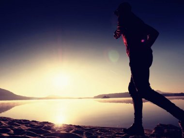  egzersiz ve göl kumsalda güneş doğarken uzanan bir adam. Sağlıklı bir yaşam tarzı. Yalnız genç fitness adam egzersiz sabah kumsalda