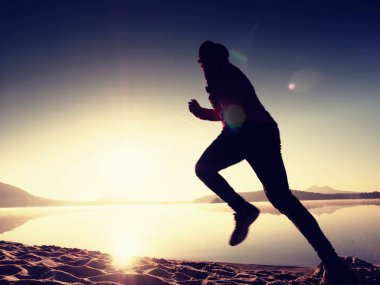  egzersiz ve göl kumsalda güneş doğarken uzanan bir adam. Sağlıklı bir yaşam tarzı. Yalnız genç fitness adam egzersiz sabah kumsalda