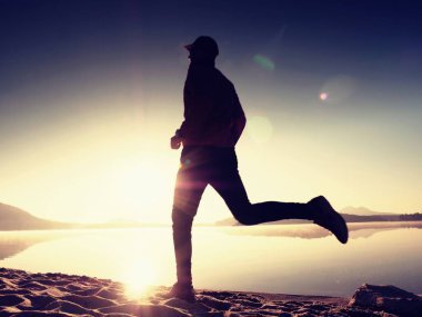  egzersiz ve göl kumsalda güneş doğarken uzanan bir adam. Sağlıklı bir yaşam tarzı. Yalnız genç fitness adam egzersiz sabah kumsalda