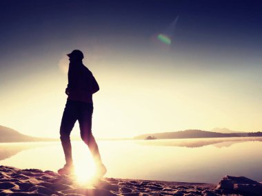  egzersiz ve göl kumsalda güneş doğarken uzanan bir adam. Sağlıklı bir yaşam tarzı. Yalnız genç fitness adam egzersiz sabah kumsalda