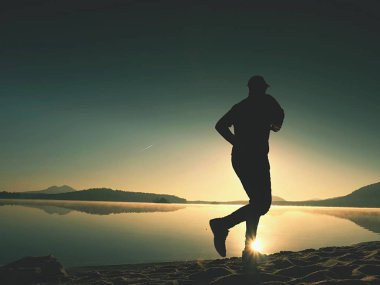  egzersiz ve göl kumsalda güneş doğarken uzanan bir adam. Sağlıklı bir yaşam tarzı. Yalnız genç fitness adam egzersiz sabah kumsalda