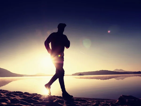 Homme exerçant et s'étendant sur la plage du lac au lever du soleil. Mode de vie sain. Seul jeune homme de fitness exercice à la plage du matin — Photo