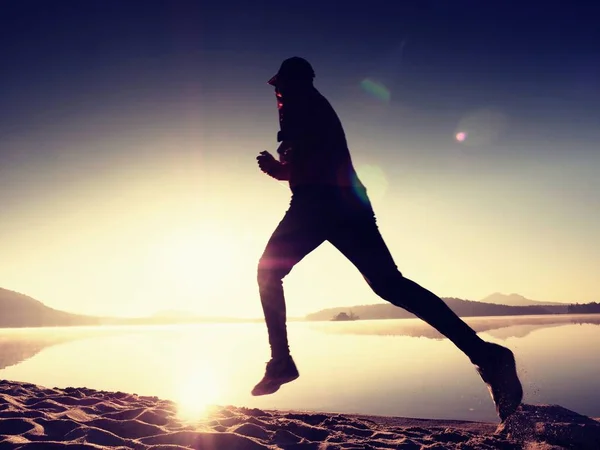 Silueta de atleta activo corriendo en la orilla del amanecer. Ejercicio de estilo de vida saludable —  Fotos de Stock