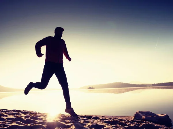 Homem exercitando e alongando-se na praia do lago ao nascer do sol. Estilo de vida saudável. Sozinho jovem fitness homem exercício na praia da manhã — Fotografia de Stock