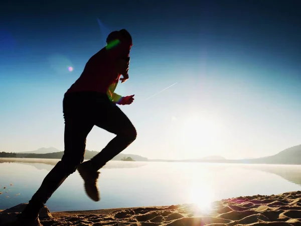 Hombre haciendo ejercicio y estirándose en la playa del lago al amanecer. Estilo de vida saludable. Solo joven fitness hombre ejercicio en la playa de la mañana —  Fotos de Stock