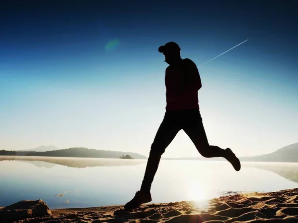 Hombre haciendo ejercicio y estirándose en la playa del lago al amanecer. Estilo de vida saludable. Solo joven fitness hombre ejercicio en la playa de la mañana — Foto de Stock