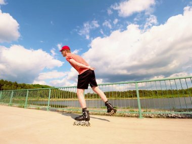 Arkadan görünüş için satır içi kırmızı tişört ve siyah pantolon köprüde paten patenci. Açık paten 
