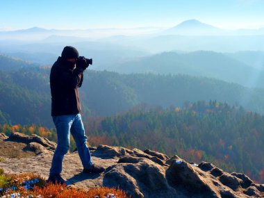 Profesyonel fotoğrafçı kaya tepe üzerinde ayna kamera ile fotoğraf çeker. Rüya gibi sis