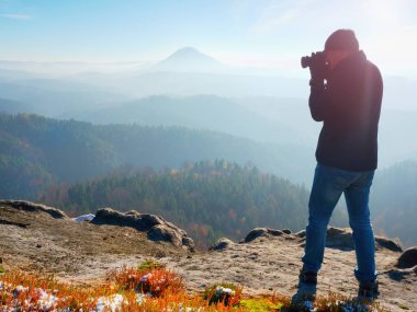 Profesyonel fotoğrafçı kaya tepe üzerinde ayna kamera ile fotoğraf çeker. Rüya gibi sis