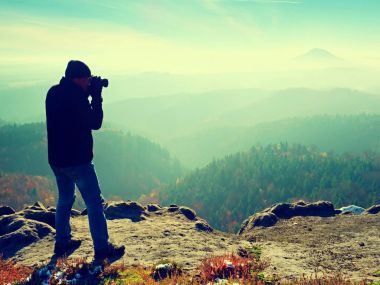 Profesyonel fotoğrafçı kaya tepe üzerinde ayna kamera ile fotoğraf çeker. Rüya gibi sis