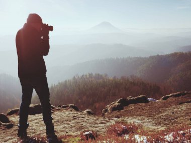 Profesyonel fotoğrafçı kaya tepe üzerinde ayna kamera ile fotoğraf çeker. Rüya gibi sis